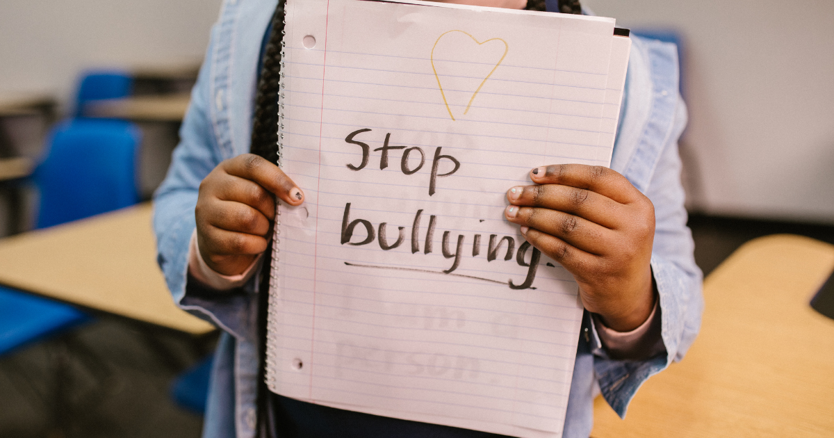 4 Recursos esenciales de apoyo contra el acoso: un niño sostiene un cuaderno con las palabras "Stop Bullying" escritas con rotulador.
